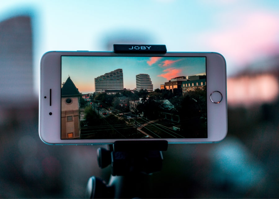 Telemóvel em tripé com vista de cidade no ecrã ao cair do dia - Apps para editar vídeos diretamente no telemóvel